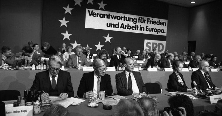 SPD-Parteitag in Köln, von links Hans Jochen Vogel, Helmut Schmidt, Willy Brandt, Katharina Focke, Herbert Wehner auf dem Podium sitzend, dahinter Motto "Verantwortung für Frieden und Freiheit in Europa", 19.11.1983. (CC-BY-SA 3.0/ Bundesarchiv, B 145 Bild-F066930-0012 / Wegmann, Ludwig)